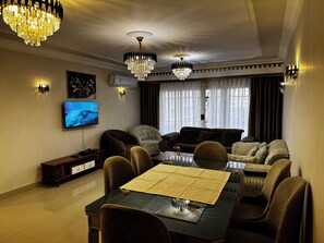 A modern living room with a dining table, multiple sofas, and two chandeliers. - Stylish 3-bedroom apartment with AC in Nasr city, Near to Cairo Airport (Nasr City)