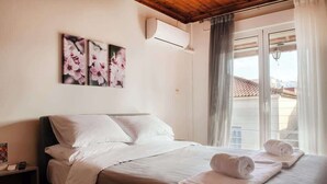 Habitación de hotel con cama, almohadas, mesita de noche, equipo de aire acondicionado y ventana con cortinas.