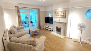 Ein Wohnzimmer mit Sofa, Fernseher, Kamin und Ventilator.
