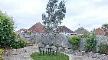 A patio area with a stone floor, a circular seating arrangement, and a wooden fence.