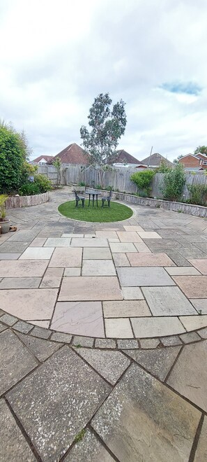 Ein Patio mit Steinboden, einer Sitzgruppe in Kreisform und einem Holzzaun.