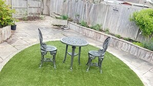 Eine runde Terrasse mit Tisch und vier Stühlen, umgeben von einer Steinsicht.
