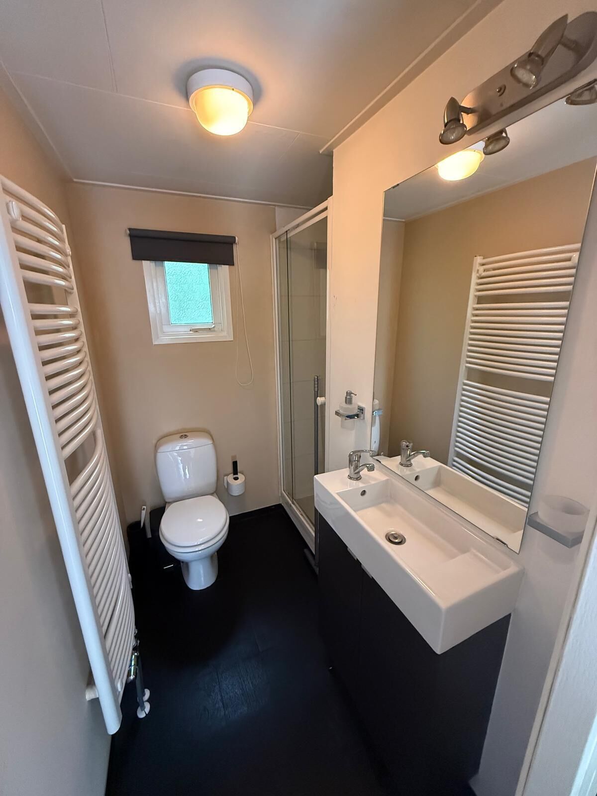 A compact bathroom with a toilet, sink, and shower.