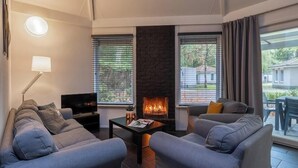 Un salon moderne avec une cheminée, deux canapés, une table basse et un téléviseur.