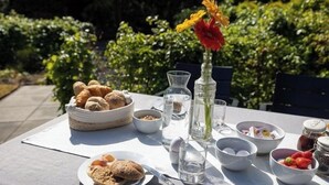 Une table dressée à l’extérieur, avec une variété d’aliments, notamment du pain, une assiette de biscuits et un bol de fraises.