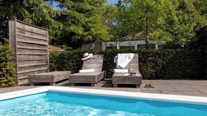 Une piscine avec des chaises longues et une clôture en bois.