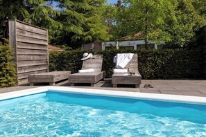 Ein Schwimmbecken mit Liegestühlen und einem Holzzaun.