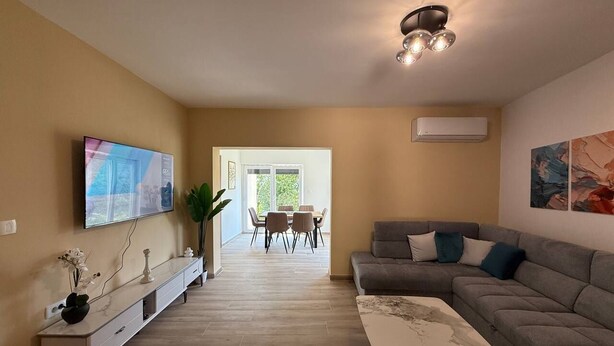 A living room with a sofa, TV, and a dining area in the background. - Top Hill Villa AnastaZija, Ivanovici, Budva (Boreti)