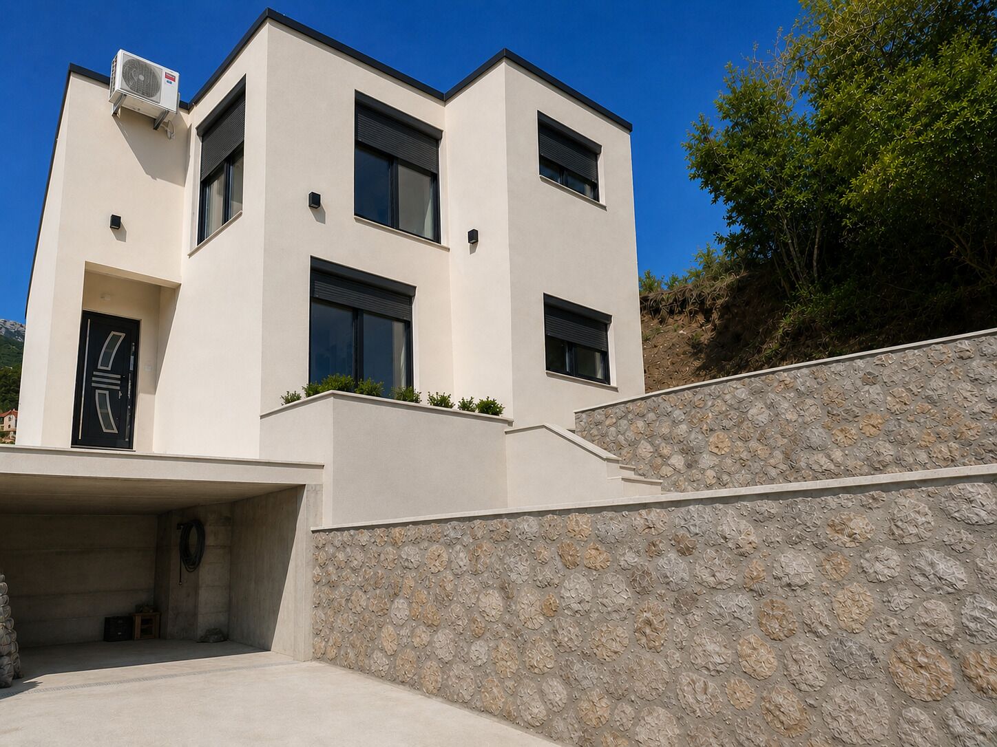 Un bâtiment moderne à deux étages, doté d’un toit plat, d’une façade en pierre et d’une entrée de garage.
