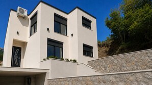 A modern two-story building with a flat roof, a stone facade, and a garage entrance. - Top Hill Villa AnastaZija, Ivanovici, Budva (Boreti)