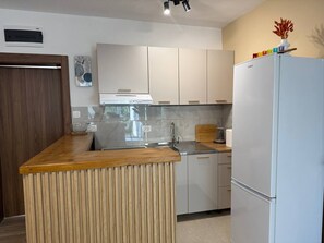 Eine Küche mit Holzarbeitsplatte, integriertem Herd, Kühlschrank und weißen Schränken.