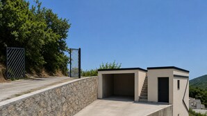 A modern building with a stone retaining wall, a gated entrance, and a staircase leading to an upper level. - Top Hill Villa AnastaZija, Ivanovici, Budva (Boreti)