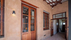 Un couloir avec des portes et des fenêtres en bois, un luminaire et un plafond avec des poutres en bois.