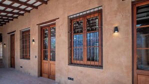 Un bâtiment doté de grandes portes et fenêtres en bois, avec des barreaux en métal, une allée couverte et des lampes fixées aux murs.