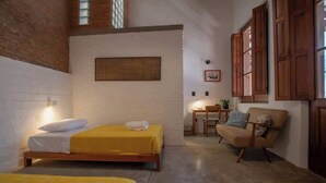 Une chambre avec deux lits, une chaise, une petite table et un panneau décoratif fixé au mur.