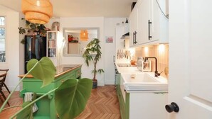Een keuken met groene kastjes, een hanglamp en een potplant.