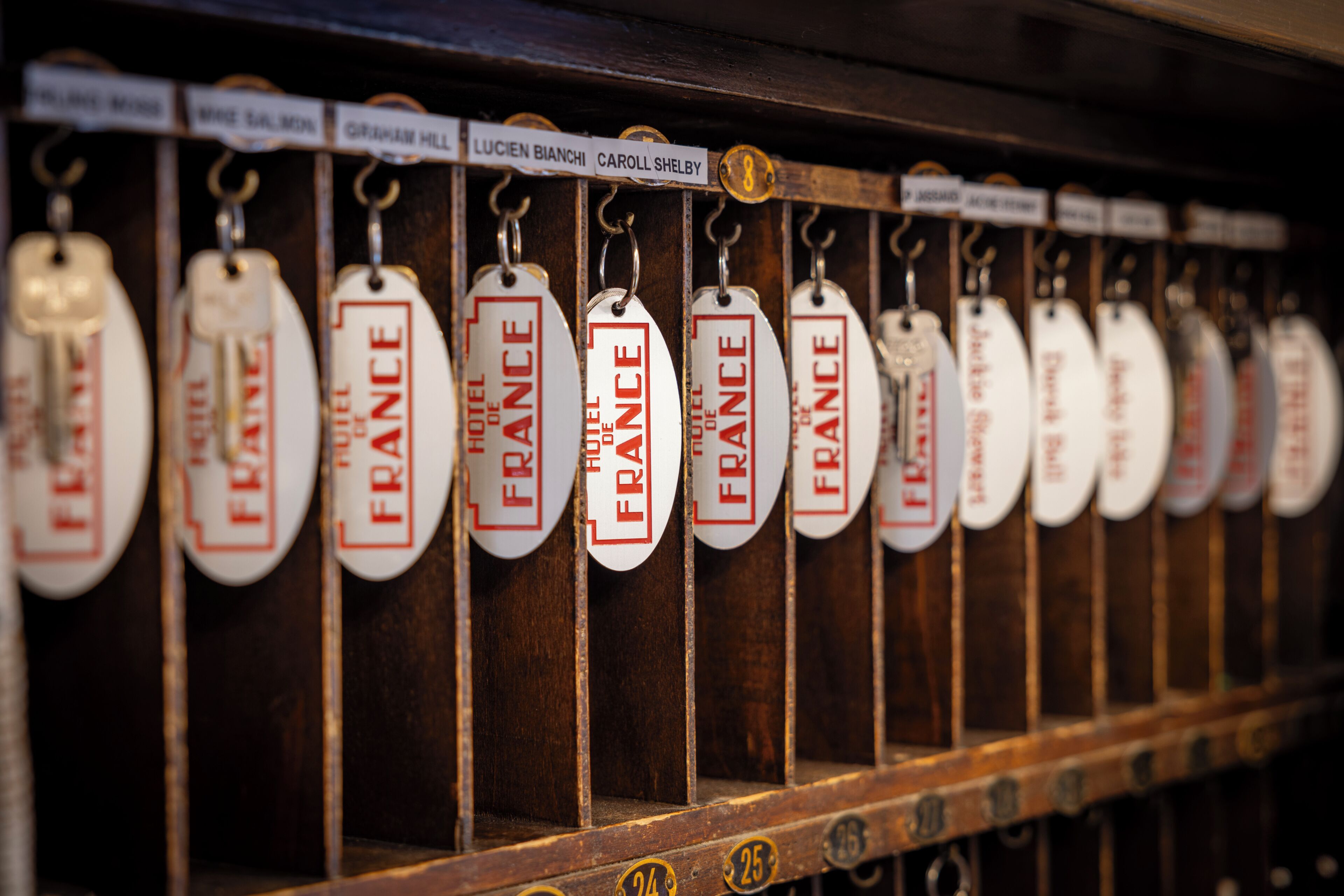 A row of hotel room tags with names and numbers.