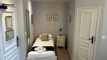 Una camera d'albergo modesta con un letto, un comodino, una lampada e una porta.