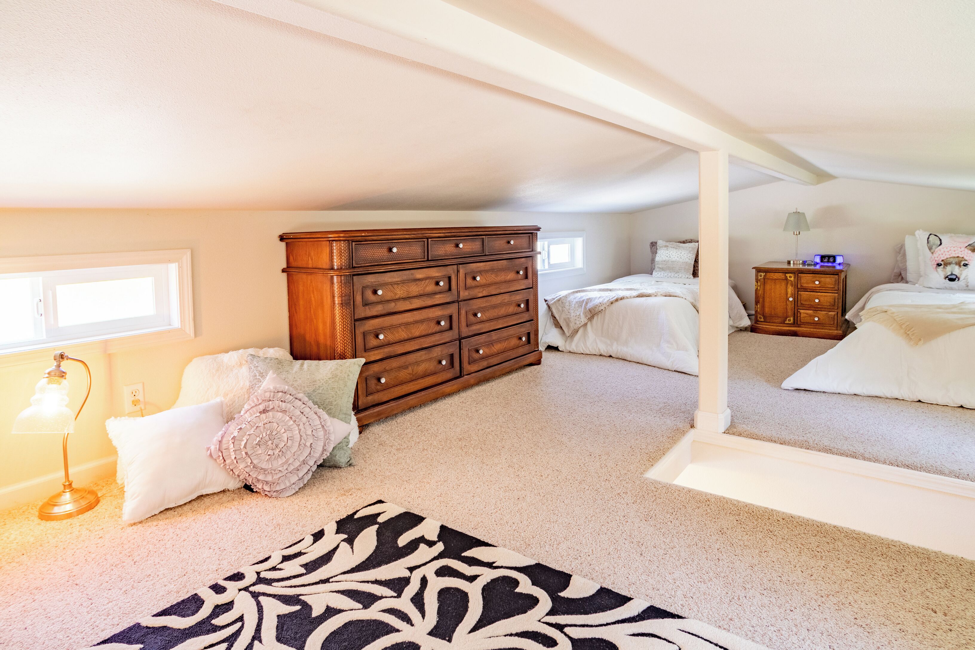 Een slaapkamer met een grote houten dressoir, een bed, een nachtkastje, een lamp en een spiegel.