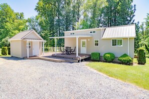 A two-story house with a covered patio, a small shed, and a well-maintained lawn. - Upscale Riverfront Getaway Cottage (Arlington)