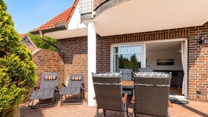 Un patio con mobili da esterno, un muro in mattoni e una porta scorrevole in vetro che dà su un ambiente interno.