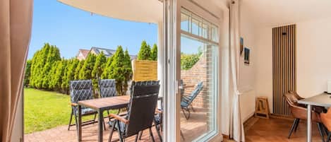 A room with a sliding glass door leading to an outdoor patio with a table and chairs.