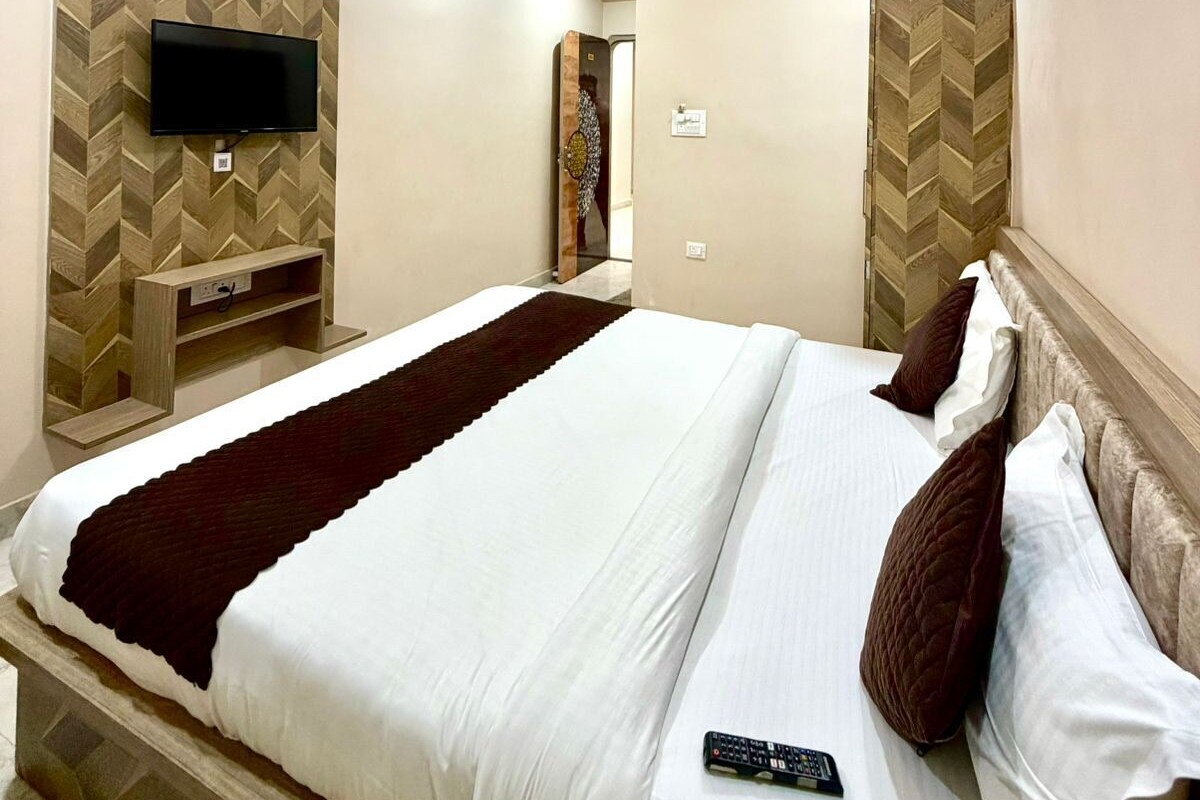 A modern hotel room with a large bed, a flat-screen TV mounted on the wall, and a ceiling fan.