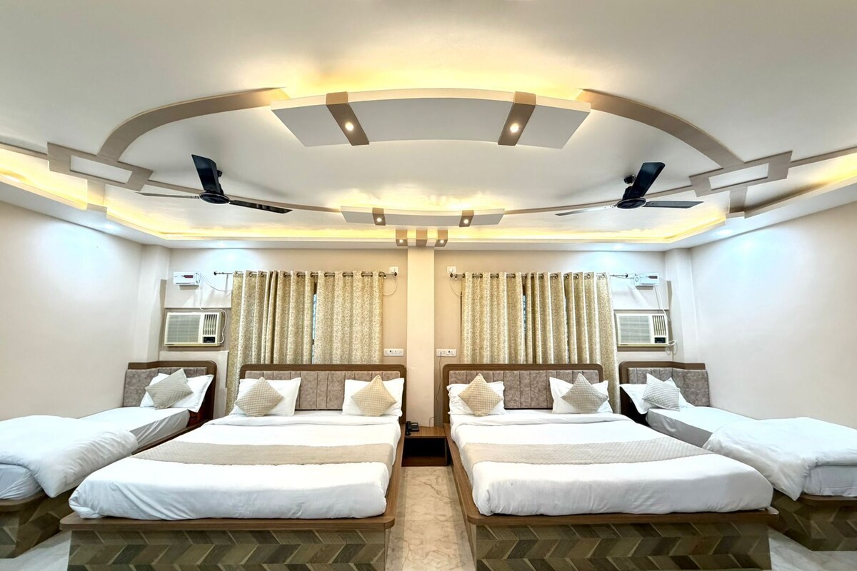 A hotel room with two beds, a ceiling fan, air conditioning units, and a herringbone-patterned floor.