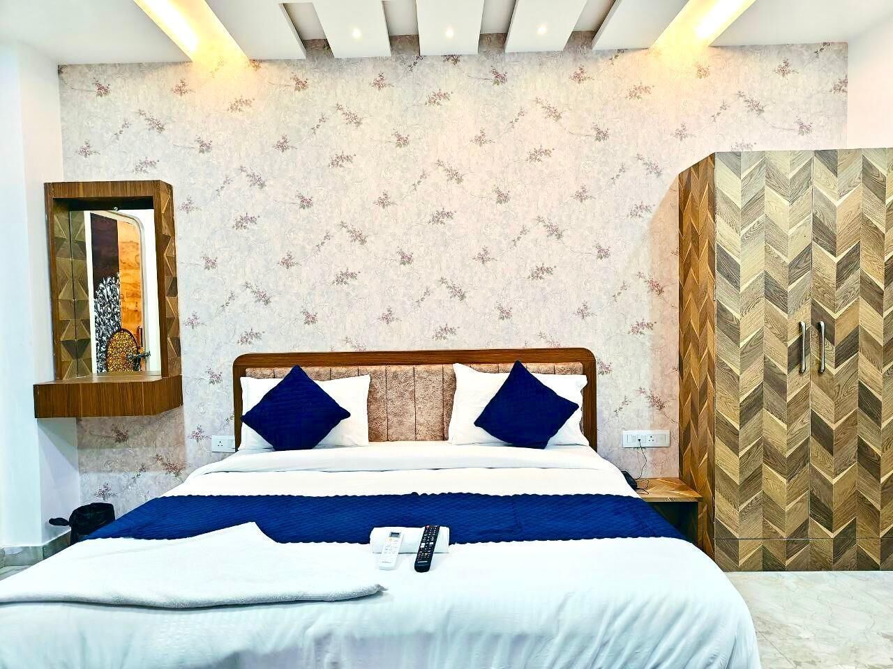 Un lit bien fait, avec une couverture bleue, une tête de lit en bois et deux oreillers bleus.