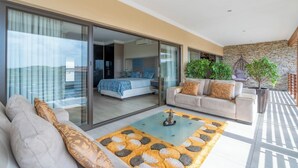 A modern bedroom with a large sliding glass door leading to a balcony, a sofa set, and a coffee table. - The Cozy Chartwell Spec (uMhlanga)