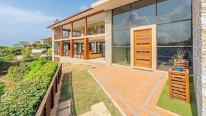 A modern two-story building with large windows, a balcony, and a stone facade. - The Cozy Chartwell Spec (uMhlanga)