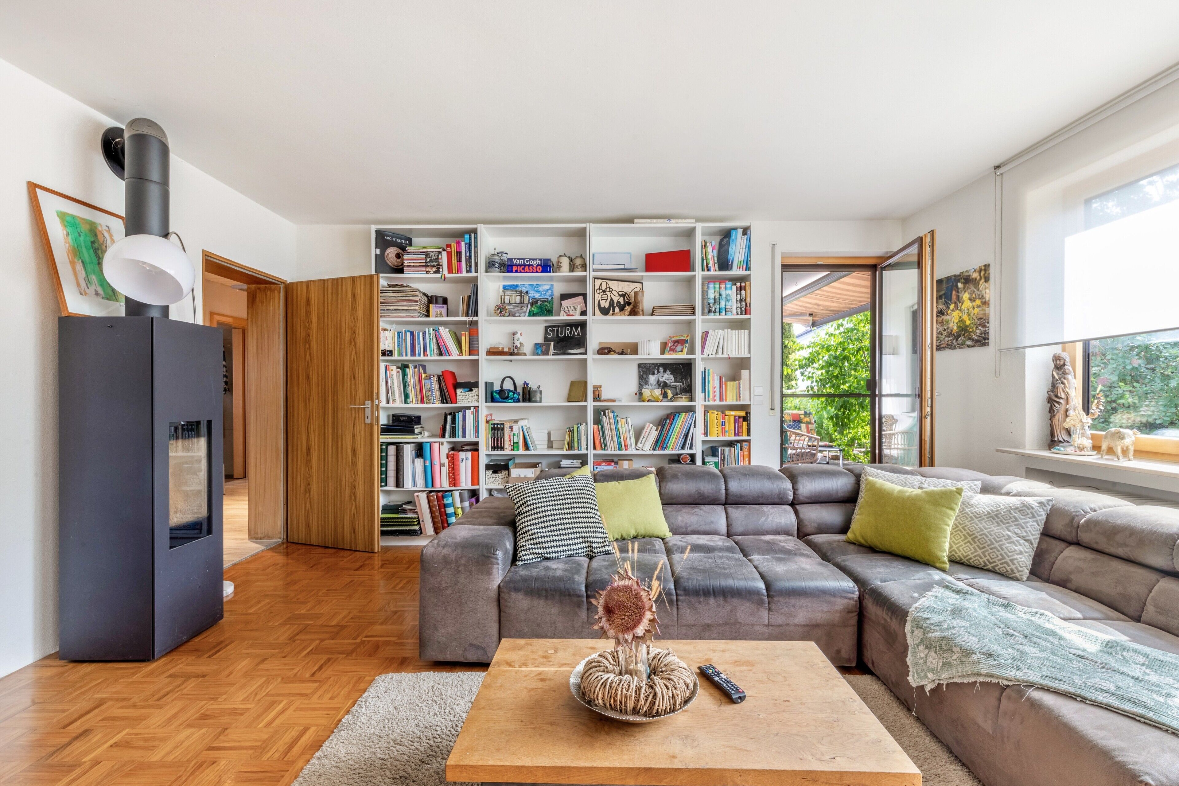Un salon moderne avec un canapé d’angle, une table basse en bois, une bibliothèque et une cheminée.