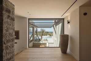 A modern interior with a stone wall, a large vase, and a view of a pool and trees. - Eleven Sundays Retreat | Beach Escape by etouri (Chania)