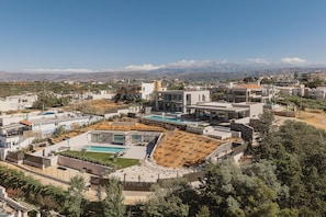 Ein Wohngebiet mit modernen Häusern, einem Swimmingpool und Blick auf ferne Berge.