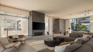 Una sala de estar moderna con chimenea, zona de estar y ventanas grandes.