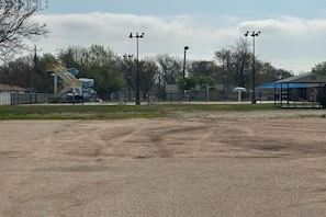 A sports field with a water slide, a covered pavilion, and street lamps.