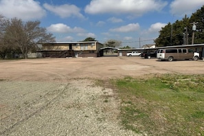 A large parking lot with a building in the background, a covered area, and several vehicles.