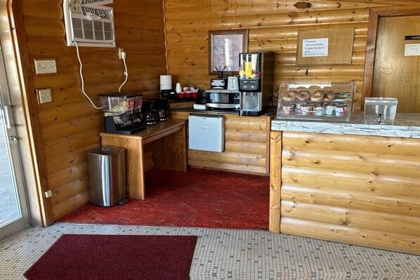 A compact kitchen with a refrigerator, microwave, coffee maker, and a small trash bin.
