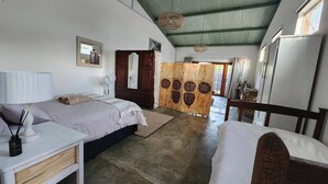 A room with two beds, a wooden wardrobe, a desk, and a chair.