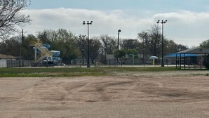 Un campo deportivo con un tobogán de agua, un pabellón cubierto y farolas.