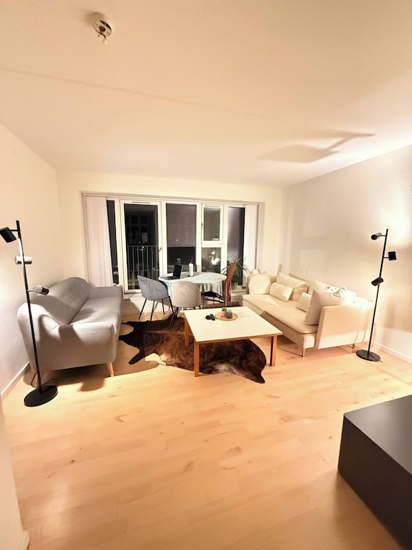 Ein modernes Wohnzimmer mit einer Couch, einem Couchtisch und einem Essbereich mit Stühlen.