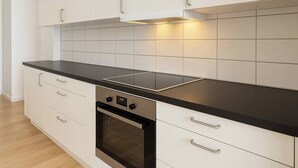 Ett modernt kök med vita skåp, en svart bänkskiva och en inbyggd ugn.