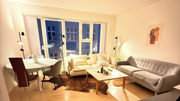 Ett vardagsrum med en soffa, ett soffbord och en matplats med ett bord och stolar.