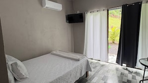 A room with a bed, a small table, a TV, and a window with curtains. - Tranquil Mountain Lodge Retreat in Fortuna, Costa Rica (Zeta trece)