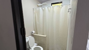 A bathroom with a toilet, a shower curtain, a white rug, and a tiled floor. - Tranquil Mountain Lodge Retreat in Fortuna, Costa Rica (Zeta trece)