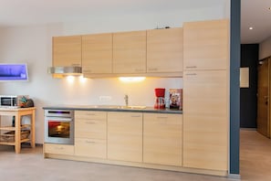 Eine moderne Küche mit Holzschränken, einem Backofen, einer Mikrowelle und einer Kaffeemaschine.