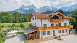 Eine zweistöckige Chalet mit Holzbalkonen, einem Teich und einer Bergkulisse.
