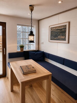 Un intérieur moderne avec une table en bois, un canapé bleu, une lanterne suspendue et un tableau encadré au mur.