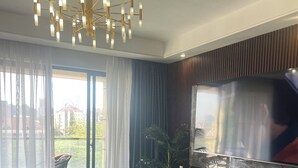 A modern living room with a sofa, a coffee table, a TV mounted on a wall, and a chandelier. - Luxury 2-bedroom, Modern Apartment, Elegant, Spacious in Kilimani Nairobi (Nairobi)
