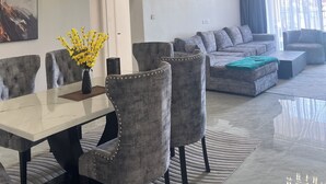 A modern living room with a sofa, a dining area with chairs and a table, and a chandelier. - Luxury 2-bedroom, Modern Apartment, Elegant, Spacious in Kilimani Nairobi (Nairobi)
